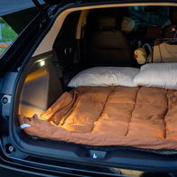 Pillows, blanket and clothes in the back of a car for camping