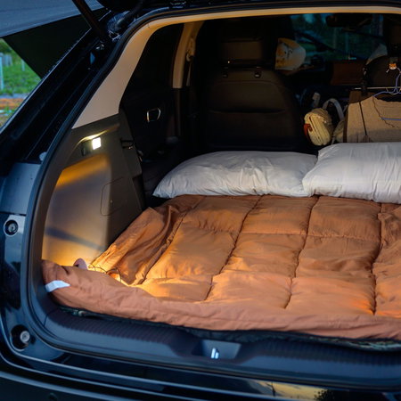 Pillows, blanket and clothes in the back of a car for camping