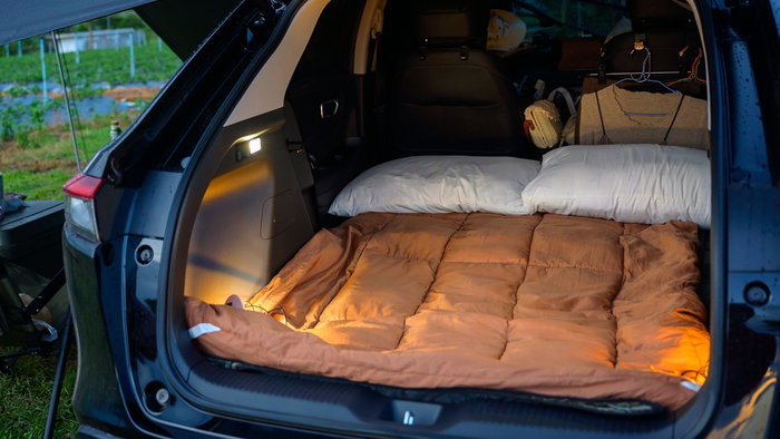 Pillows, blanket and clothes in the back of a car for camping