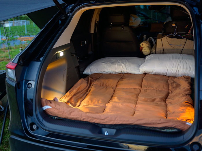 Pillows, blanket and clothes in the back of a car for camping