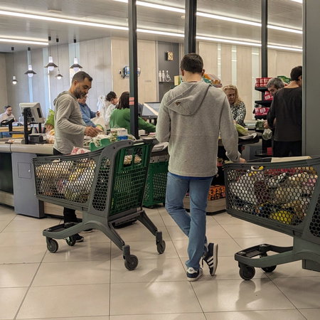 People queued at a supermarket checkout with their shopping trolleys full of food