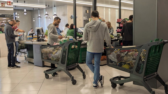 People queued at a supermarket checkout with their shopping trolleys full of food