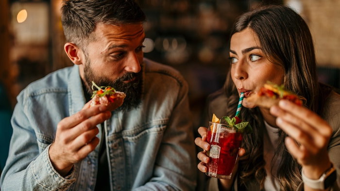 Young couple sharing tapas and drinks, enjoying a date night out