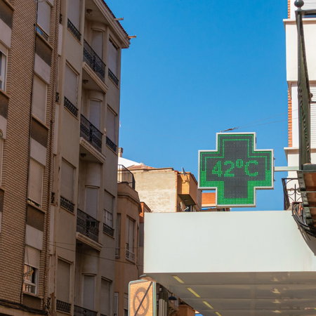 Green cross thermometer above a pharmacy in Spain indicating 42º