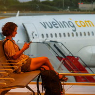 Woman siting in an airport with a Vueling aircraft in the background