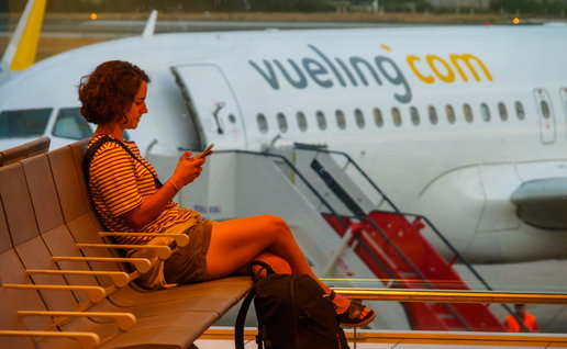 Woman siting in an airport with a Vueling aircraft in the background