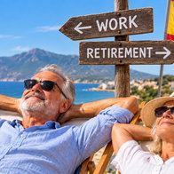 Couple relaxing in Spain beside a sign pointing to work and retirement
