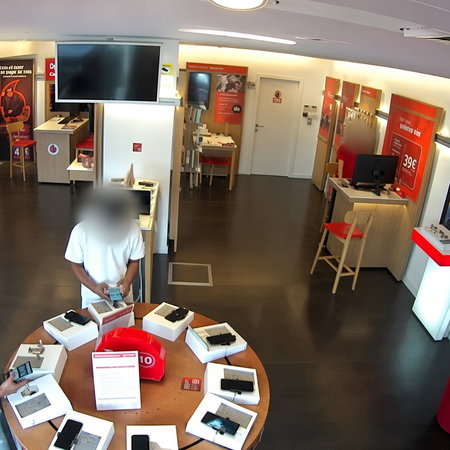 A phone shop with two individuals with faces blurred out looking at mobile phones