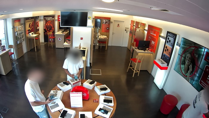 A phone shop with two individuals with faces blurred out looking at mobile phones