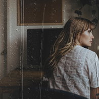 Woman looking through a rain-covered window as Airbnb introduces new holiday rain insurance