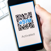 Hand holding a mobile phone with a QR code on the screen for eSim saying activated