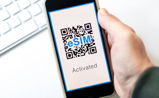 Hand holding a mobile phone with a QR code on the screen for eSim saying activated