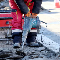 Worker repair the road surface with a jackhammer. Construction work, laying of paving slabs in city