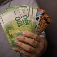 Person holding a fan of euro banknotes, illustrating savings and investment in Spain.