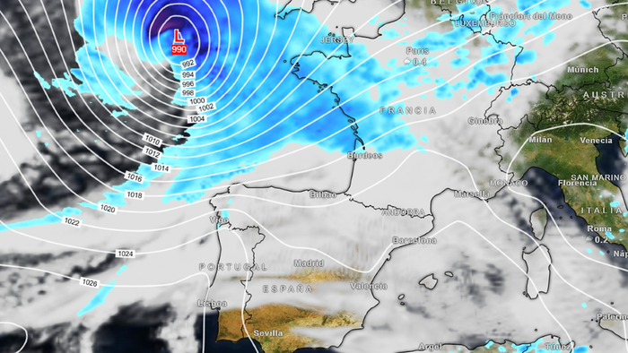 Weather map of western Europe showing a deep low-pressure system marked L 990 to the north-west of France, ringed by curved white pressure lines, with blue bands of rain over the sea, the English Channel and France, and mostly cloudy but dry skies over Spain and Portugal.