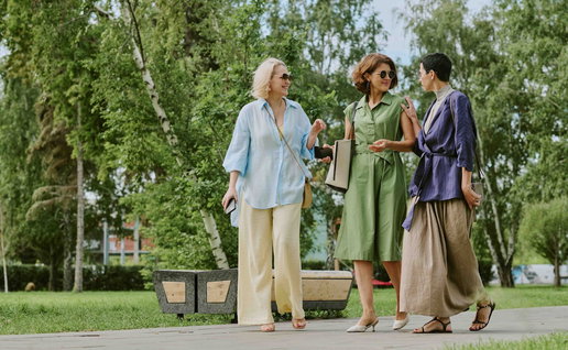 Three women walking through a park.
