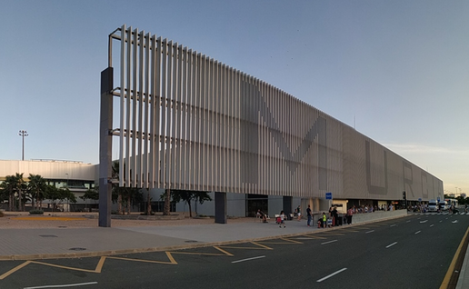 The exterior of Murcia airport's terminal building at dusk, with its slatted facade and passengers waiting at the kerb.