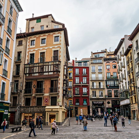 People walking past colourful buildings in Pamplona’s historic centre, Navarra, Spain.