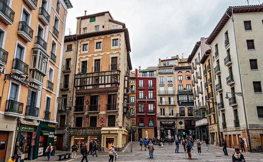 People walking past colourful buildings in Pamplona’s historic centre, Navarra, Spain.