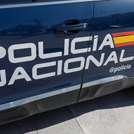 Side of a dark blue Spanish police car with the words Policía Nacional and the Spanish flag colours on the door.