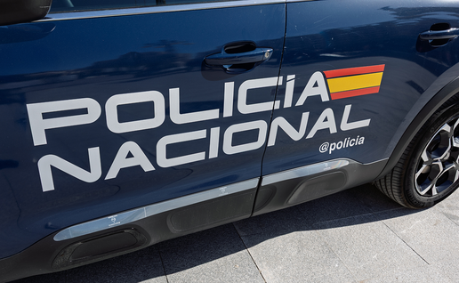 Side of a dark blue Spanish police car with the words Policía Nacional and the Spanish flag colours on the door.