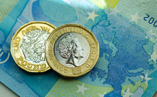 Two British one pound coins resting on a blue euro banknote.