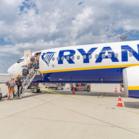Passengers boarding a Ryanair aircraft via stairs at an airport.
