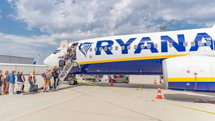 Passengers boarding a Ryanair aircraft via stairs at an airport.