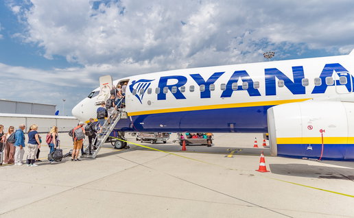 Passengers boarding a Ryanair aircraft via stairs at an airport.