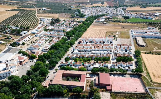 Aerial view of a whitewashed Spanish village with terracotta roofs, olive groves, and surrounding farmland.