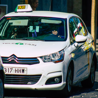 A taxi on the road queued behind another car.