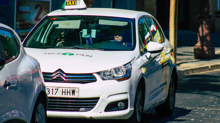 A taxi on the road queued behind another car.