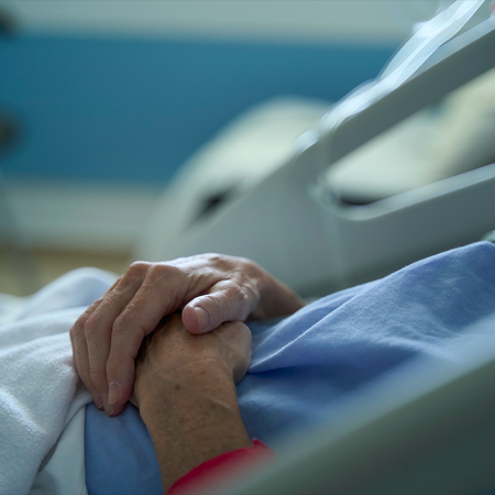 Hands on a man lying on a hospital bed