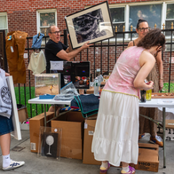 People in the street looking at a yard sale stall.