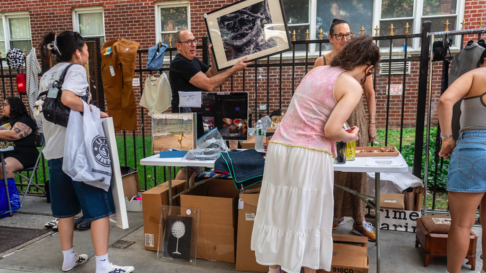 People in the street looking at a yard sale stall.