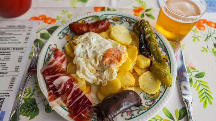 A traditional meal from Spain with fried egg, potatoes, black pudding, ham and fried peppers