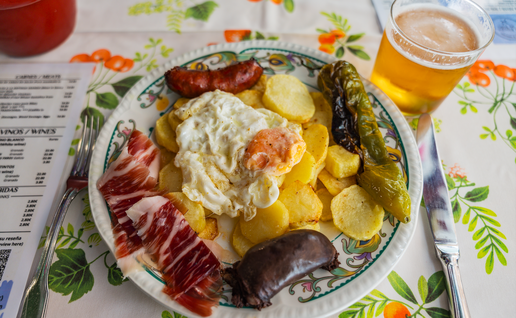 A traditional meal from Spain with fried egg, potatoes, black pudding, ham and fried peppers