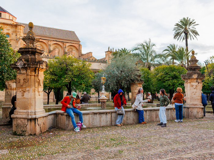Tourists sitting on a wall outside a monument in Cordoba