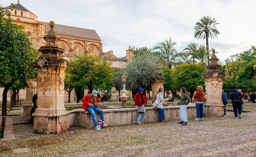 Tourists sitting on a wall outside a monument in Cordoba