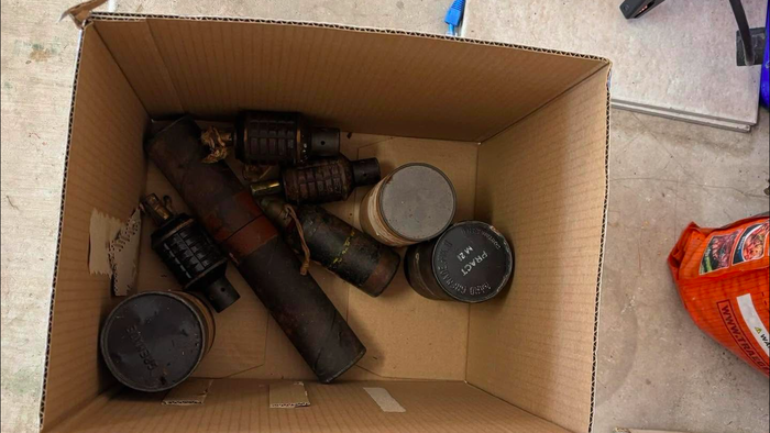 A cardboard box with a selection of hand grenades and mortar rounds inside