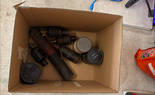 A cardboard box with a selection of hand grenades and mortar rounds inside