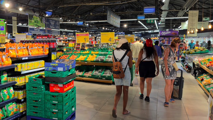 Shoppers in a supermarket surrounded by produce
