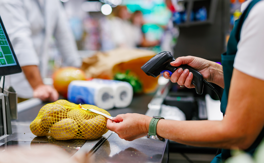 The hand of a cashier at the till scanning the price tag on a bag of potatoes
