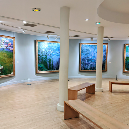 A museum room with paintings of Claude Monet and wooden benches in front of them
