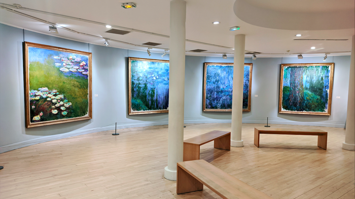 A museum room with paintings of Claude Monet and wooden benches in front of them