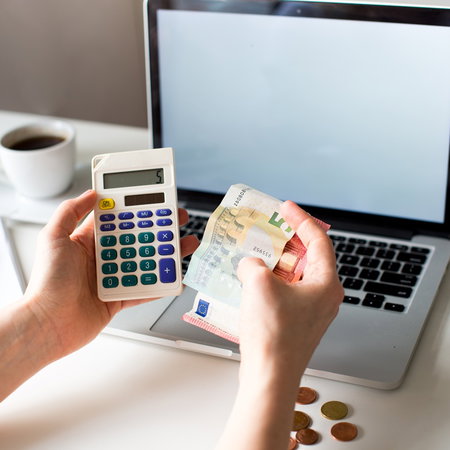 Worker calculating salary deductions with euro banknotes