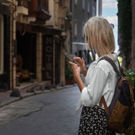 Young female looking at her mobile phone while visiting a beautiful street in Istanbul