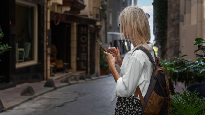 Young female looking at her mobile phone while visiting a beautiful street in Istanbul