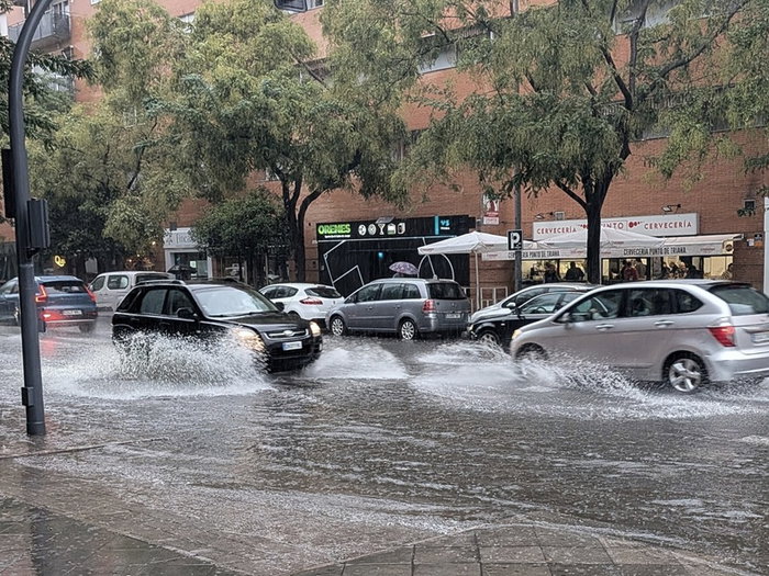 Cars drive through a flooded street in Spain following heavy rainfall.