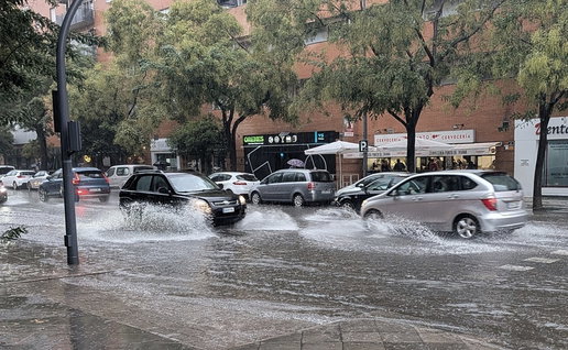 Cars drive through a flooded street in Spain following heavy rainfall.